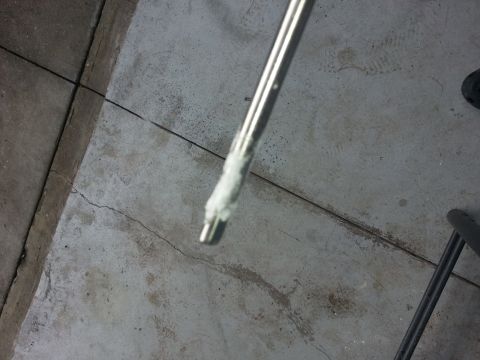 1994 Ford Bronco - Close-up of a metal rod with white paste, likely a tool or part, on a concrete surface.