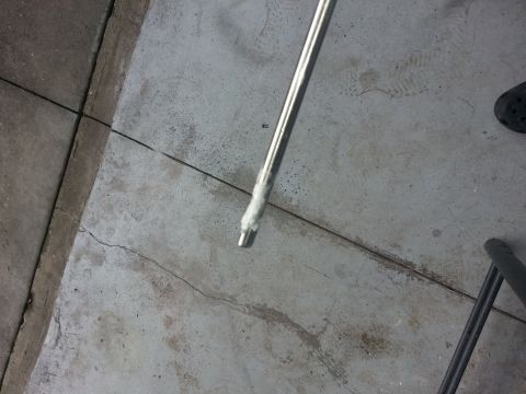1994 Ford Bronco - A close-up view of a dipstick, likely from a vehicle, on a concrete surface.