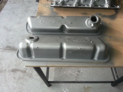 1994 Ford Bronco - Two Ford valve covers are shown, one stacked on top of the other, on a workbench.