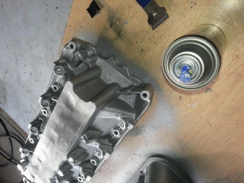 1994 Ford Bronco - An engine intake manifold is prepped for painting with a spray can and masking tape nearby.
