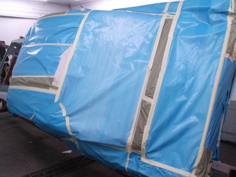 1967 Ford Mustang - A vehicle is covered in blue plastic sheeting and tape, likely in a workshop or garage setting.