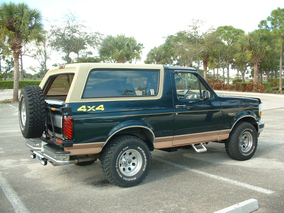 Dark green 1994 Ford Bronco with tan top and trim, spare tire mounted on rear carrier