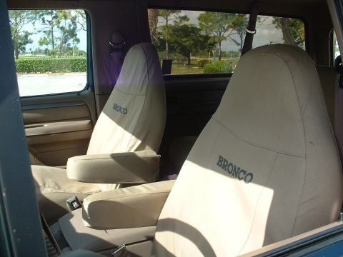 1994 Ford Bronco - Tan seat covers with "BRONCO" lettering are visible inside the vehicle's interior.