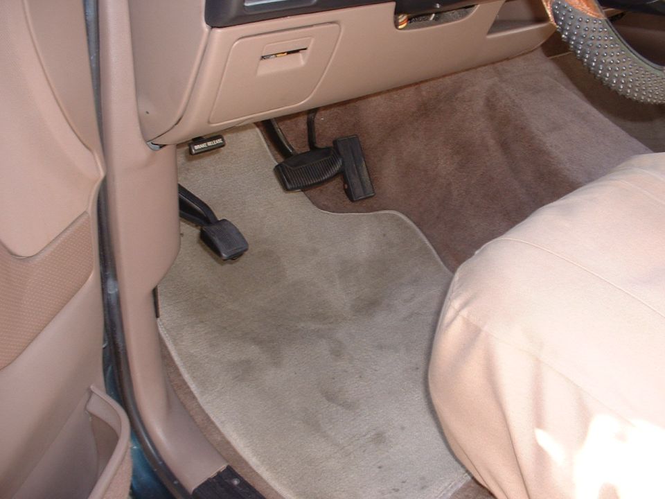 driver's side footwell with pedals and carpet