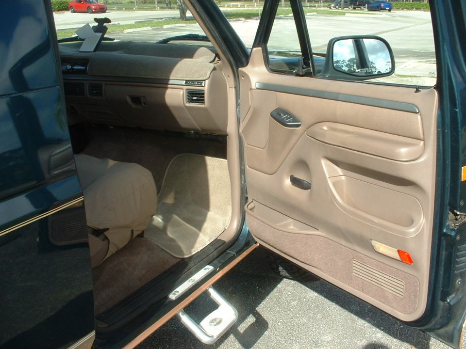 Interior door panel and dashboard of a dark green SUV. Beige seats and carpet visible