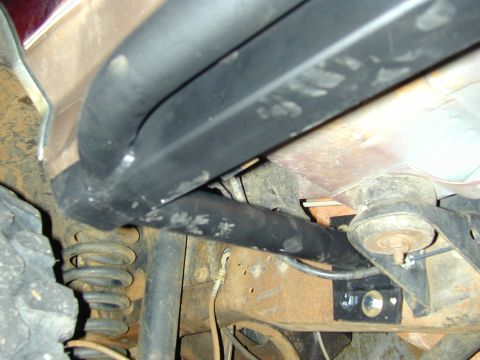 1996 Ford Bronco - Close-up view of the undercarriage reveals suspension parts and a side step, with visible rust on the frame.