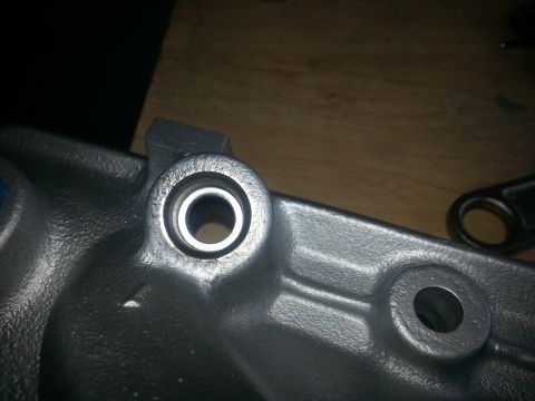1994 Ford Bronco - A close-up view of a metal engine component is shown against a wooden background.
