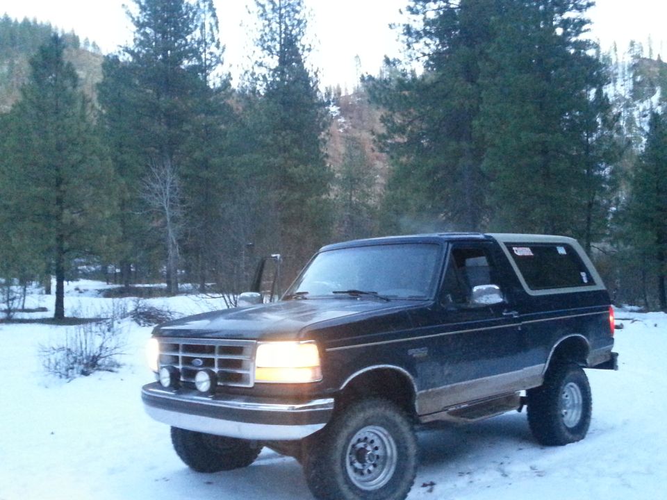 Dark blue Ford Bronco with tan lower body trim parked in snow, front-left quarter view