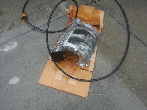 1994 Ford Bronco - An engine intake manifold is shown on a concrete surface, placed on cardboard.