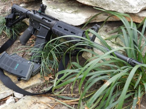1996 Ford Bronco - An AR-15 style rifle and two loaded magazines are placed on the ground amidst rocks and foliage.