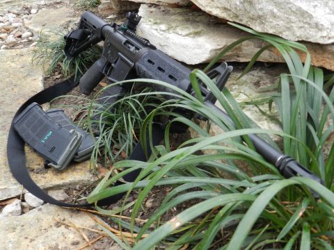 1996 Ford Bronco - An assault rifle and two magazines are partially obscured by grass and rocks.