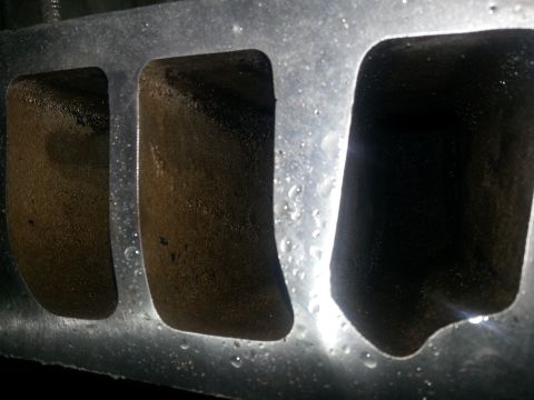 1994 Ford Bronco - Close-up of a wet engine intake manifold with visible ports and a Supermotors.net watermark.