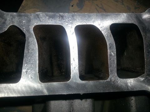 1994 Ford Bronco - Close-up of a dirty intake manifold, showing significant carbon deposits within its ports.