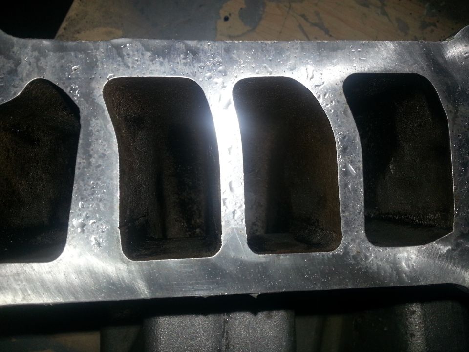 Intake manifold with four ports, covered in black carbon buildup