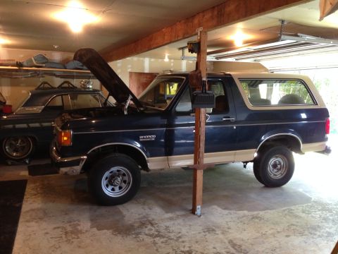 1990 Ford Bronco - A 1990 Ford Bronco is parked in a garage with its hood up, next to another vehicle.