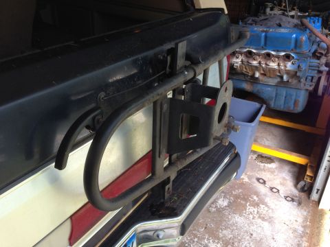 1990 Ford Bronco - Spare tire carrier mount on the rear bumper of a vehicle.