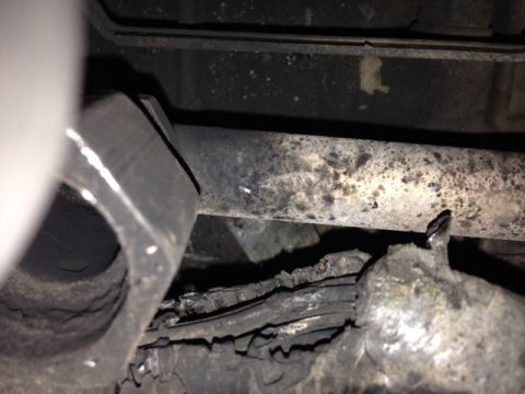 1996 Ford Bronco - Damaged exhaust pipe and heat shield showing signs of wear and tear.