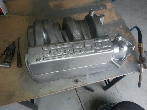 1994 Ford Bronco - Ford 5.0 intake manifold on a workbench, next to a screwdriver and air tool.