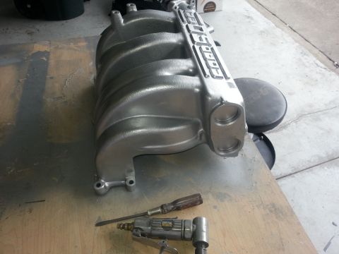 1994 Ford Bronco - An engine intake manifold with 'FORD' branding is shown on a workbench with tools nearby.