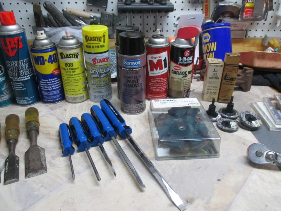 Assortment of spray cans, screwdrivers, chisels, and other tools on a workbench