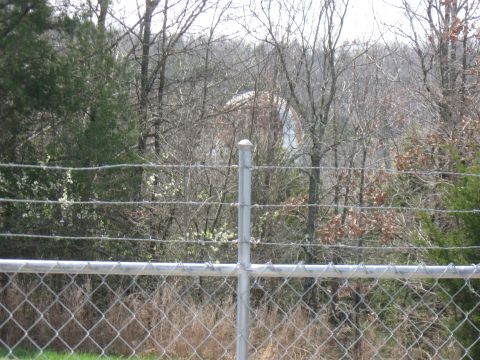 2006 Suzuki DR-Z400S - A water tower is visible in the distance, partially obscured by trees and a chain-link fence.