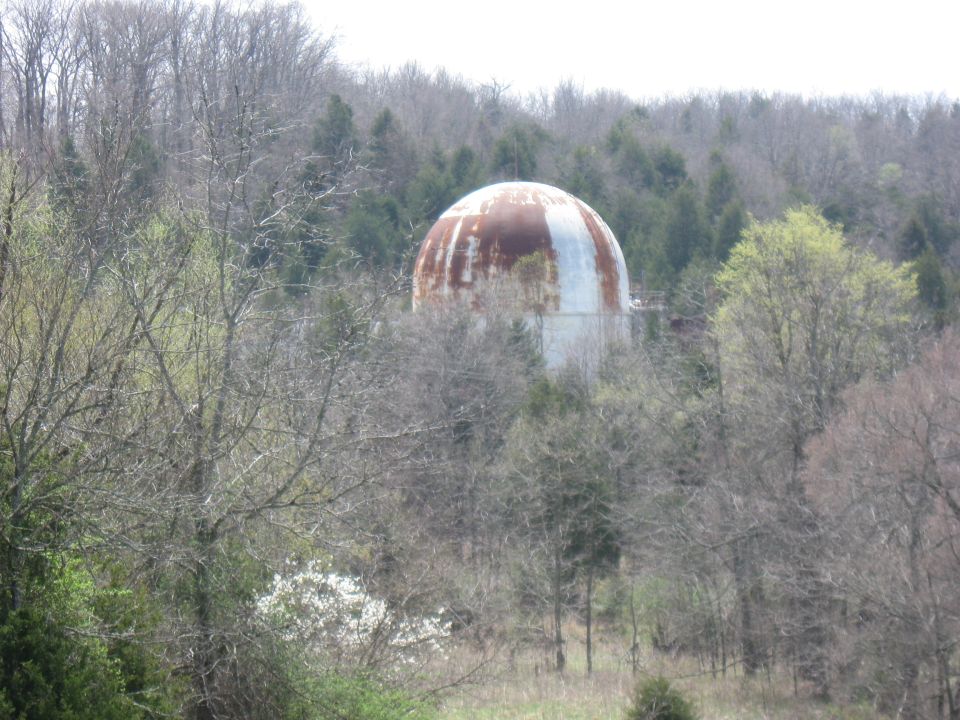 Large, rusty, domed structure in a wooded area