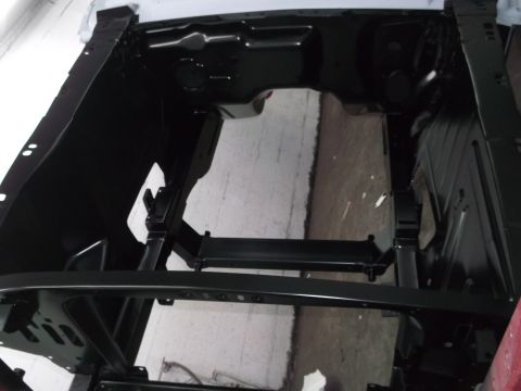 1967 Ford Mustang - The bare frame of a car is visible, painted black, with structural elements exposed.