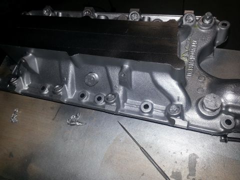 1994 Ford Bronco - A close-up view of a silver engine intake manifold, showing cast-in part numbers and bolt holes.