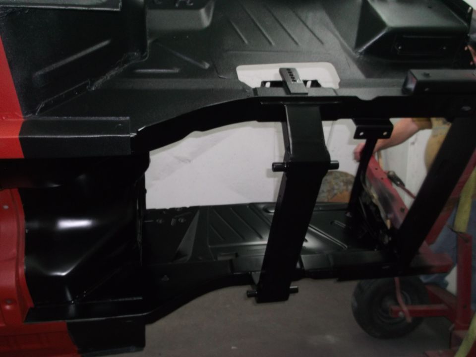 Car chassis with black undercoating and red exterior paint visible