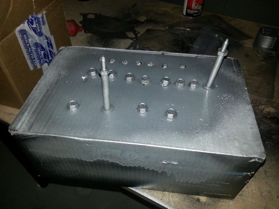 Metal box with multiple bolts and studs on top, some protruding