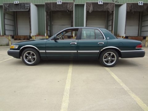 1993 Mercury Grand Marquis - A green sedan is parked in front of industrial loading docks.