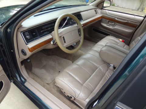 1993 Mercury Grand Marquis - The interior of a 1993 Mercury Grand Marquis features tan leather seats, a tan dashboard, and wood trim accents.