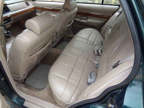 1993 Mercury Grand Marquis - The interior of a sedan features tan leather seats and wood trim accents on the doors and dashboard.