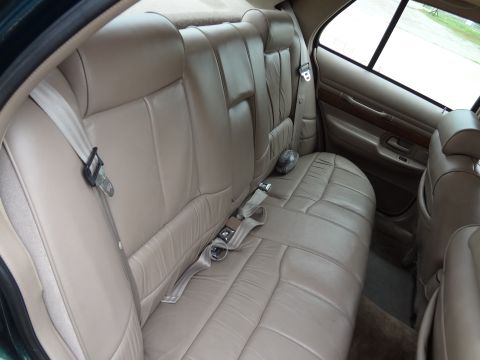 1993 Mercury Grand Marquis - The interior of a car shows tan leather rear seats and seatbelts, with watermarks on the image.