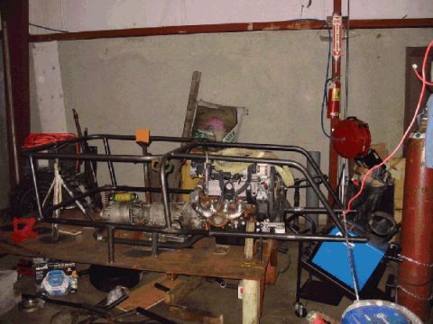 1994 Ford Bronco - A custom tube chassis is shown with an engine and transmission installed, in what appears to be a workshop setting.