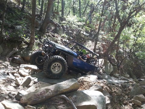 1967 Ford Mustang - A custom off-road buggy tackles a challenging rocky terrain on a wooded hillside.