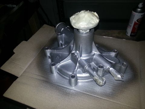 1994 Ford Bronco - A silver water pump is shown on a piece of cardboard, with its shaft masked off for painting.
