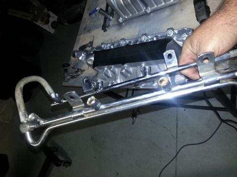 1994 Ford Bronco - A person is holding a chrome fuel rail assembly, likely for engine repair or modification.