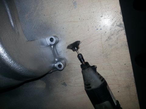 1994 Ford Bronco - A rotary tool with a wire brush cleans an aluminum engine intake manifold.