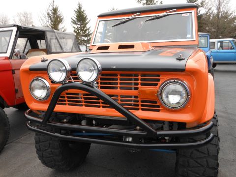 1995 Ford Bronco - This classic Ford Bronco features a custom front bumper and auxiliary lights, parked alongside another Bronco.
