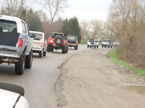 1995 Ford Bronco - A convoy of Ford Broncos and other SUVs travels down a dusty, rural road.