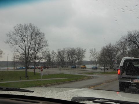 1995 Ford Bronco - Multiple vehicles are parked in a lot near a lake on an overcast day.