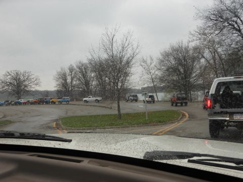 1995 Ford Bronco - A gathering of SUVs and trucks are seen in a parking area near a body of water on an overcast day.