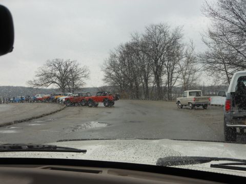 1995 Ford Bronco - Multiple vehicles, including off-roaders and trucks, are parked in an outdoor lot under a cloudy sky.