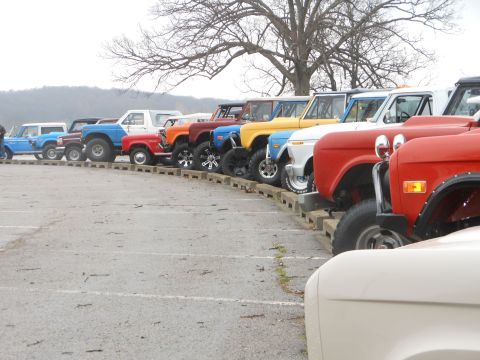 1995 Ford Bronco - A collection of Ford Broncos are parked in a row, various colors and modifications.