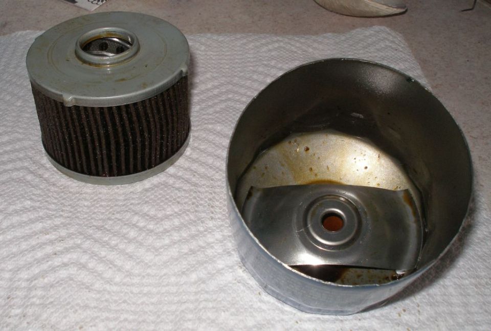 Used oil filter and its metal housing, resting on paper towels
