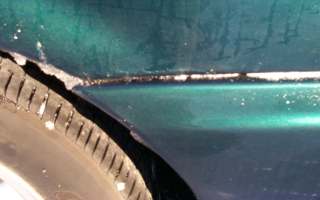 1994 Ford Taurus - A close-up view of a vehicle's side panel and tire, with visible dirt and debris.