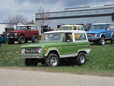 1995 Ford Bronco - Several Ford Broncos are parked on a grassy area in front of a building.