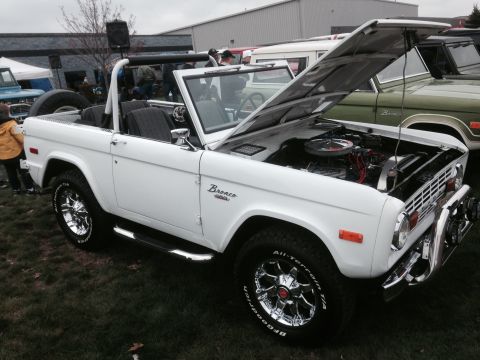 1995 Ford Bronco - A white Ford Bronco convertible is displayed with its hood open, revealing the engine bay.