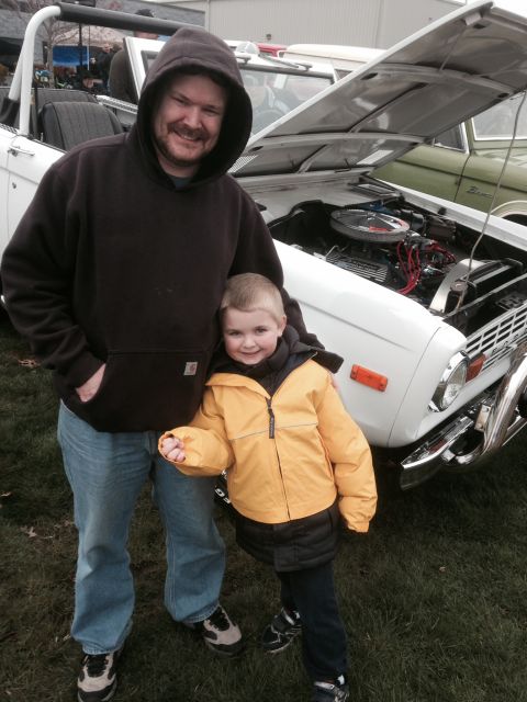 1995 Ford Bronco - Man and child pose with a white Ford Bronco at an outdoor event.
